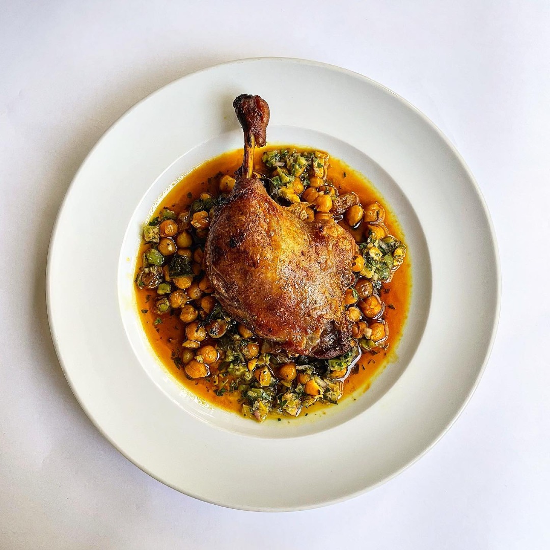 A plate of duck confit with braised chickpeas.