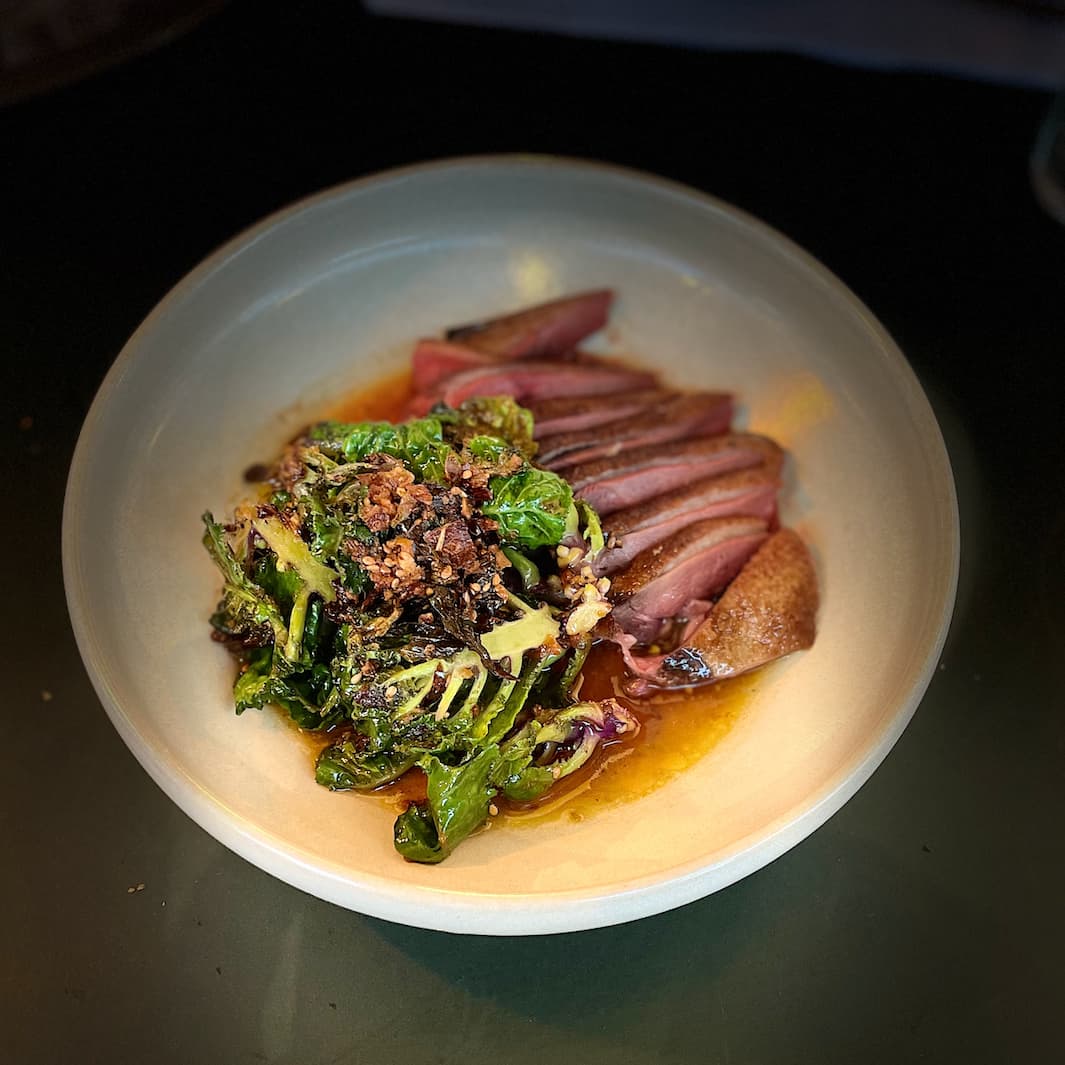 Seared duck in a rich sauce with crispy greens.